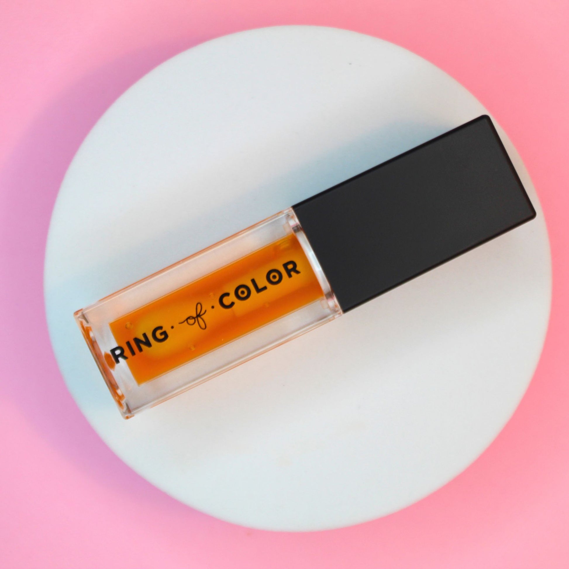 sheer orange lip oil on circular prop