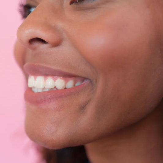 Close-up of a person's face with a pink background wearing a cream nude lip liner