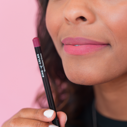 darkskin model holding berry shade liner. close up picture of her lips