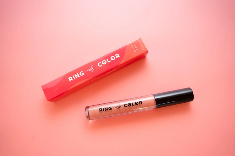 top view of peach lip lacquer next to packaging with ring of color branding on pink background