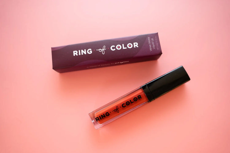 top view of matte liquid lipstick next to branded box on pink background