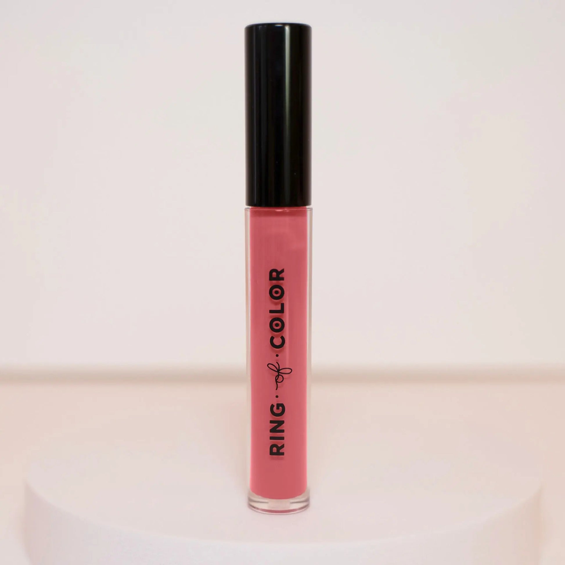 Lip gloss with black cap and pink body on a light background