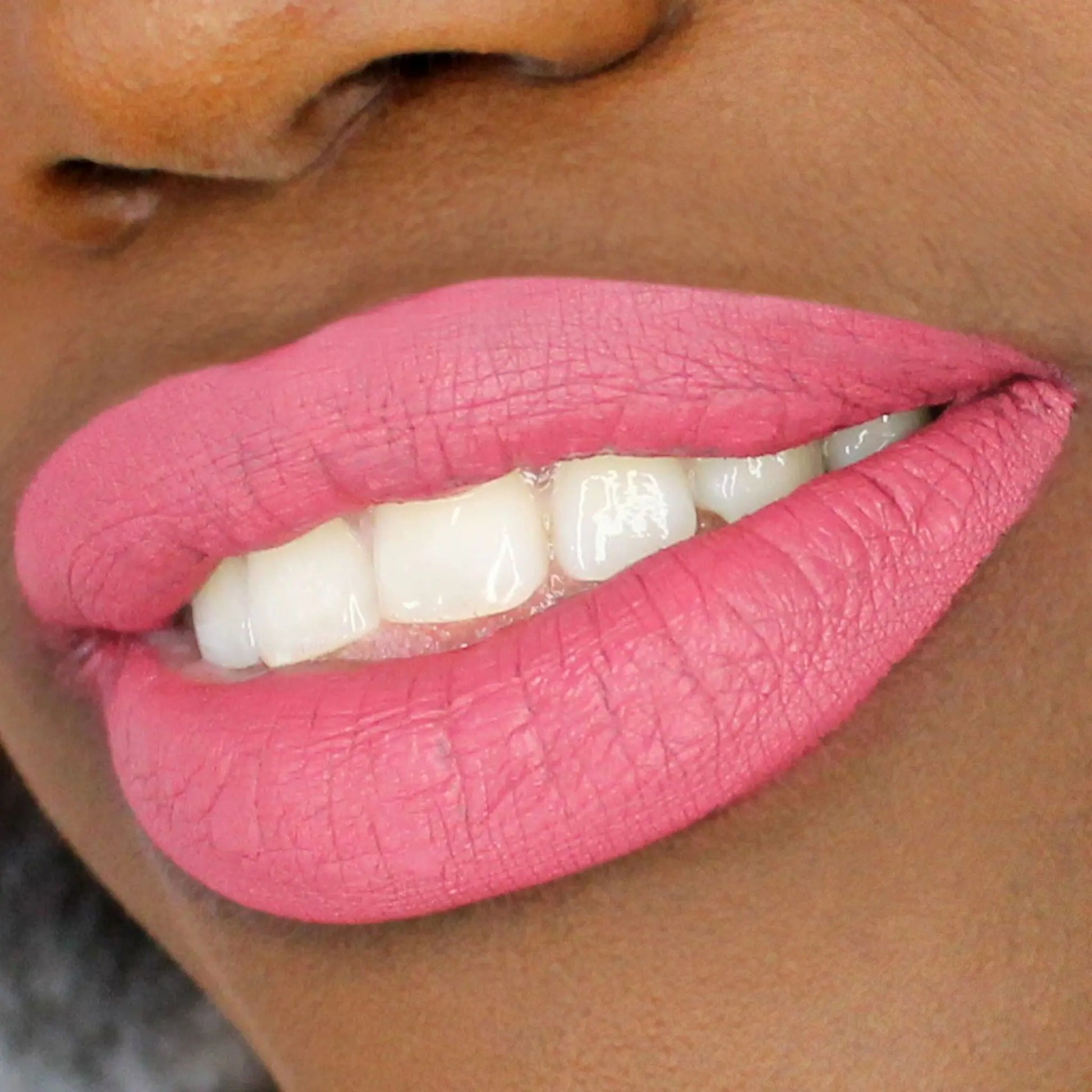 Close-up of a dark skin person wearing pink lipstick with a blurred background