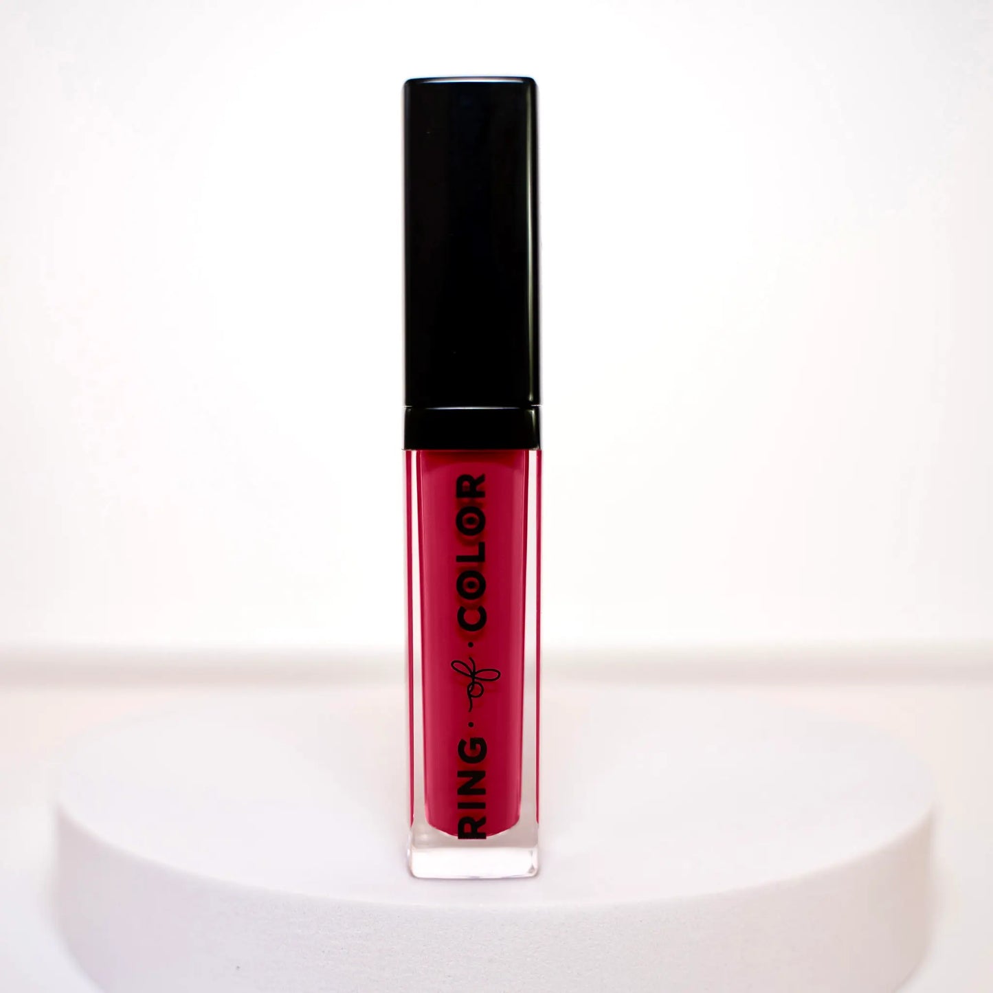 Lipstick with black cap and red liquid on a white background
