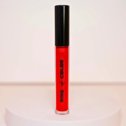 Red lip gloss with black cap on a light pink background