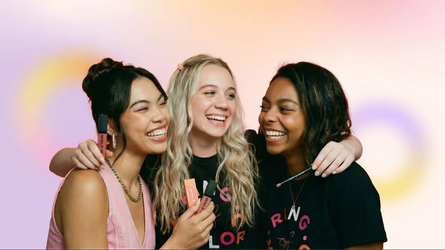 Three women smiling and embracing with a colorful background
