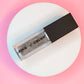 grey shimmer clear lip oil with black cap and clear vial