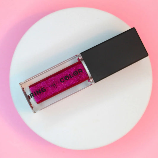 Deep Pink Berry glittery lip oil with black cap on a white and pink gradient background